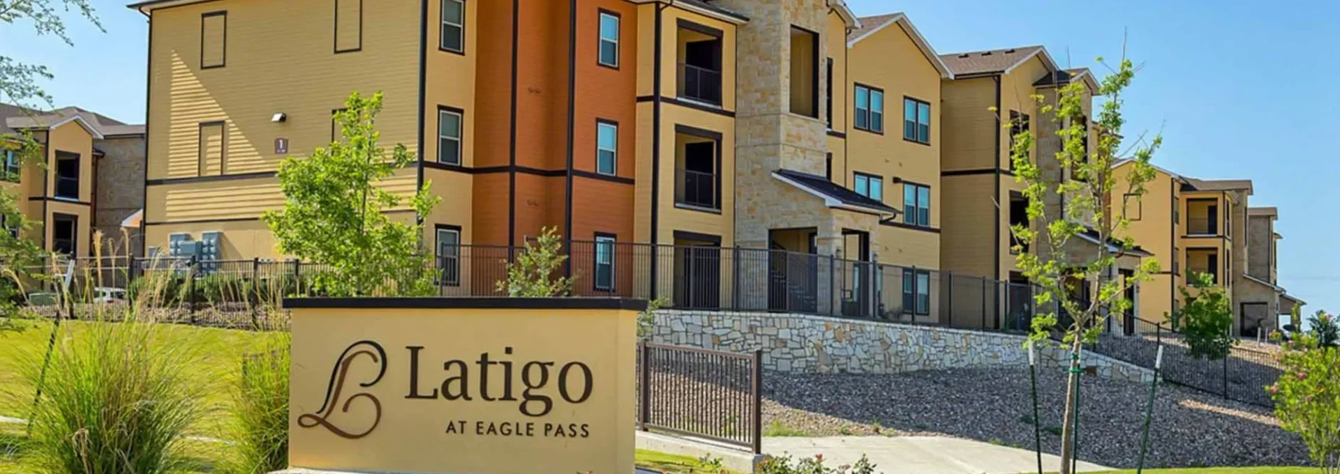 the sign for latigo apartments is in front of a building at The Latigo at Eagle Pass