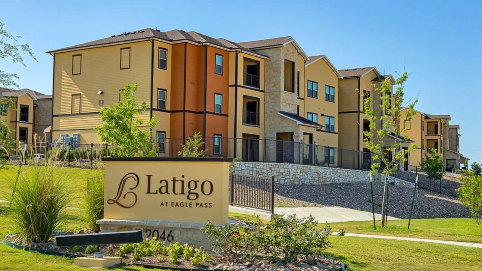 the sign for latigo apartments is in front of a building at The Latigo at Eagle Pass